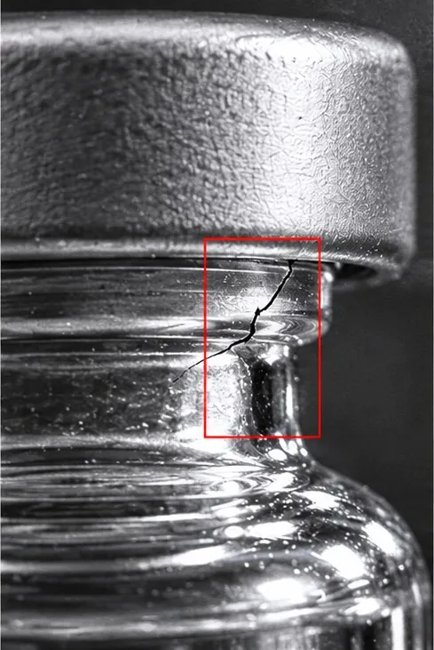 Close-up of a vial neck with a hairline crack marked by a red box