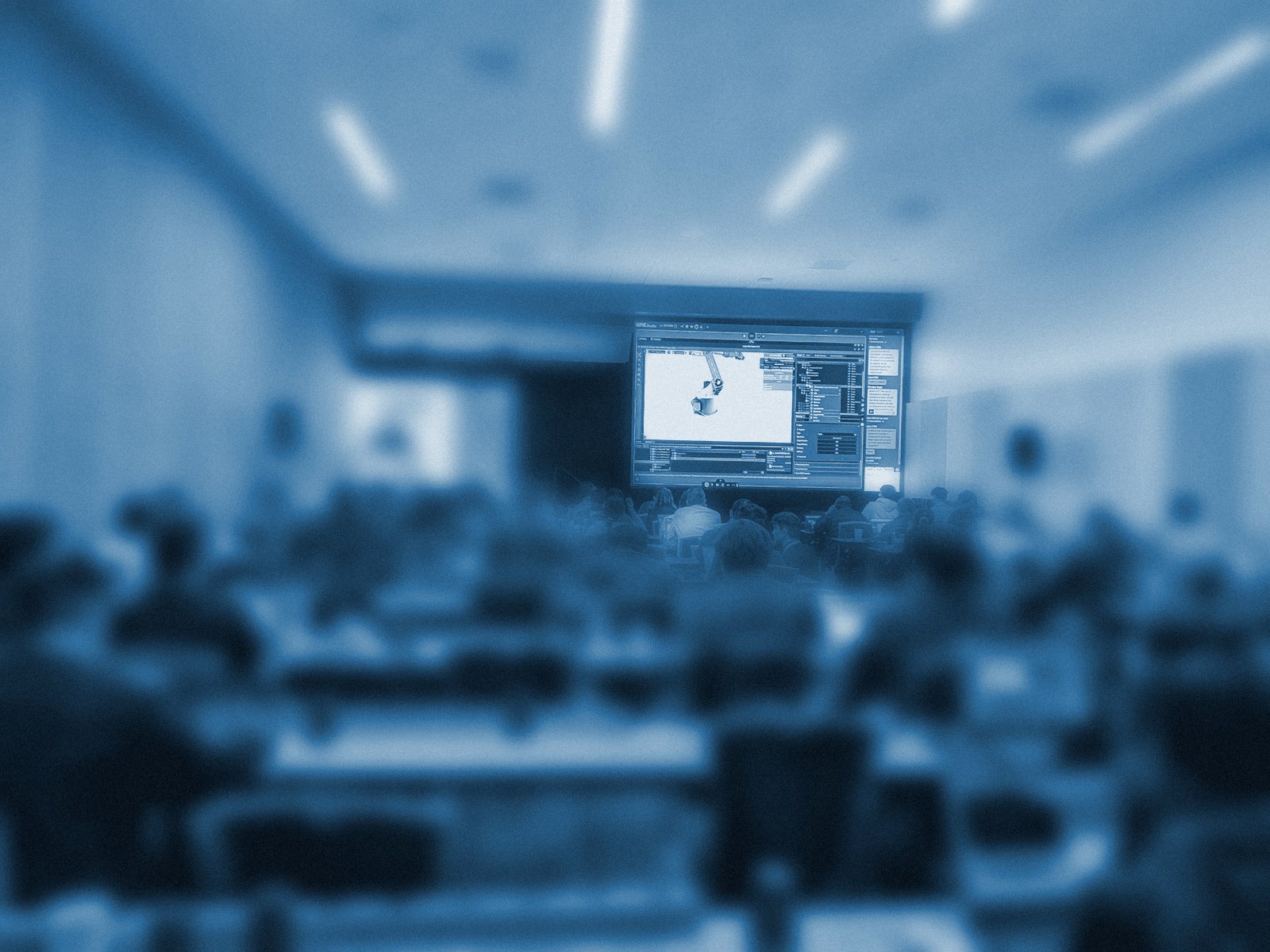 A full room at NVIDIA GTC 2026: attendees on laptops, the UME.Studio session on the main screen