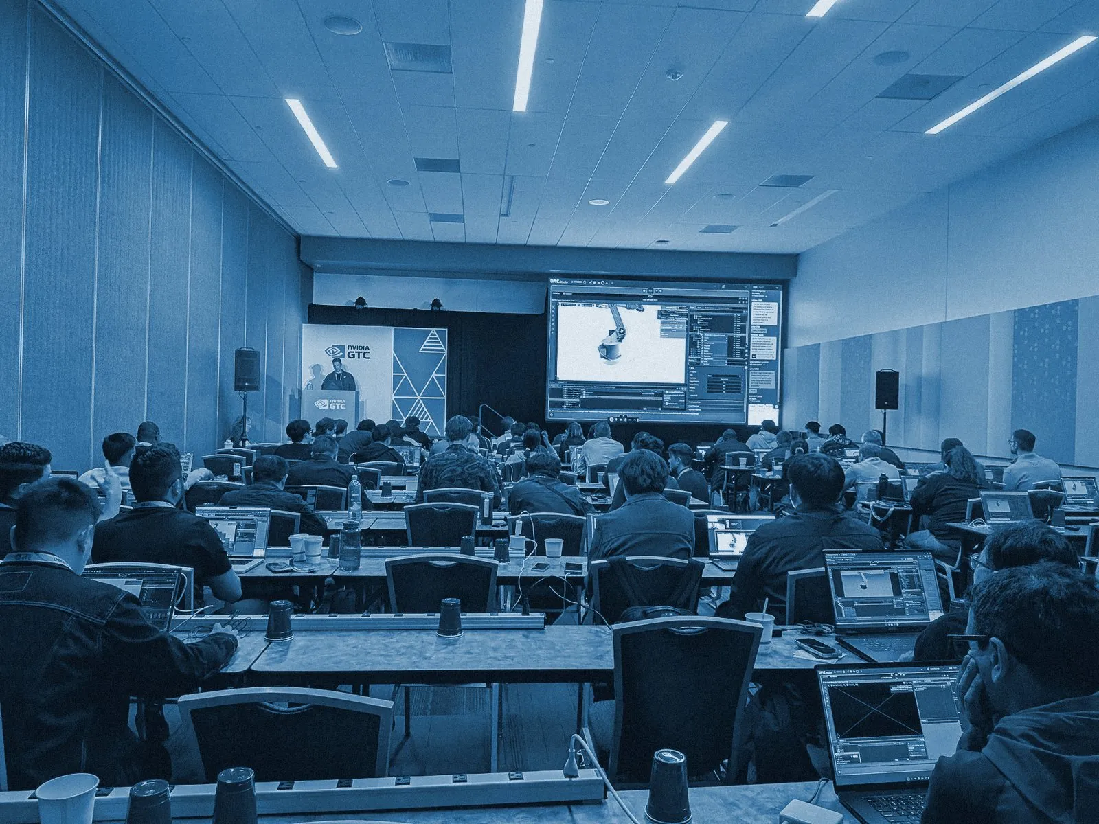 A full room at NVIDIA GTC 2026: attendees on laptops, the UME.Studio session on the main screen
